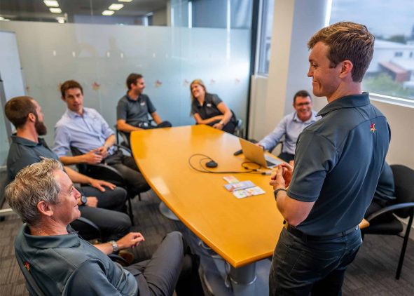 Group of professionals in an office meeting room engaged in a discussion.