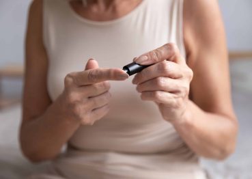 middle-aged woman using a blood glucose meter to check her sugar levels at home, highlighting diabetes management and health monitoring