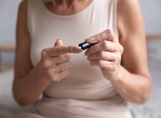 middle-aged woman using a blood glucose meter to check her sugar levels at home, highlighting diabetes management and health monitoring