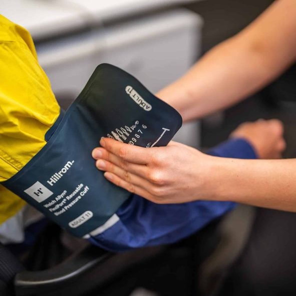 Medical professional applying a Hillrom RexPort Reusable blood pressure cuff to a patient